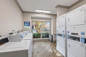 Laundry room with washers and dryers and a window at The Enclave at Crossroads, North Carolina, 27606